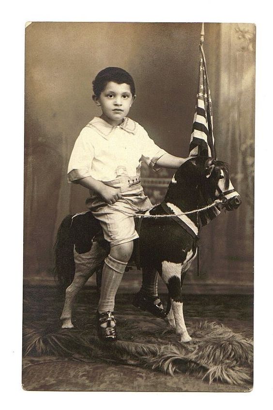 A boy on a rocking horse toy with an american flag