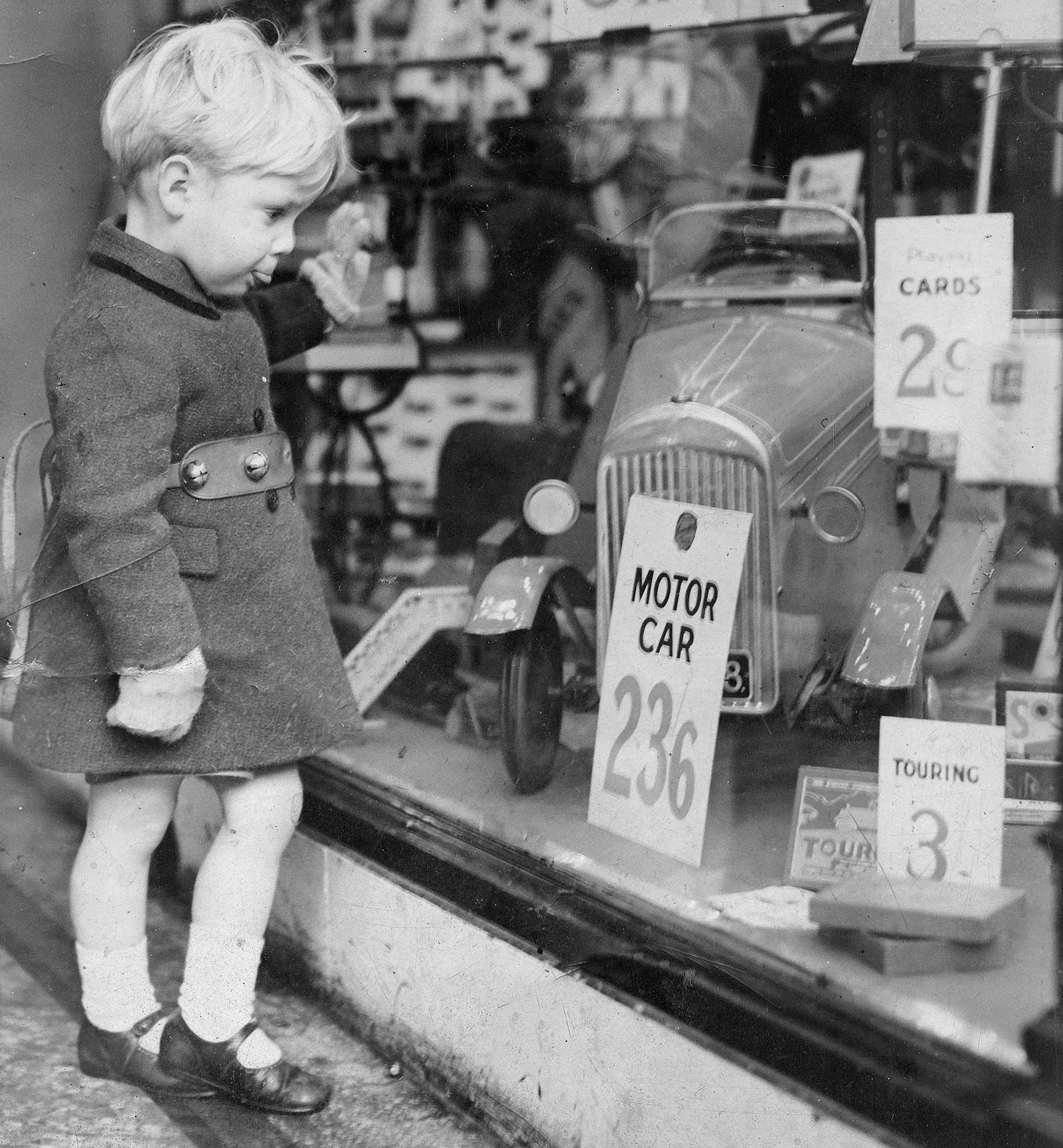 Vintage photo a boy gazing to a window shop for a toy car