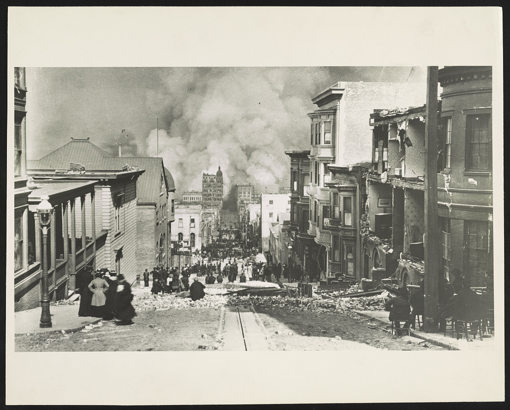 retro photograph shows people standing on Sacramento Street watching the fire after earthquake in 1906