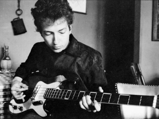 Bob Dylan plays a bass guitar in a restaurant, 1964
