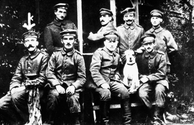 A young Hitler (farthest left at bottom row) posing with other German soldiers and their dog