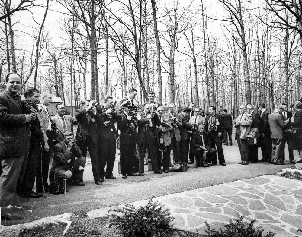 A large group of photographers and members of the press gather to observe a meeting of President John F. Kennedy and former President General Dwight D. Eisenhower at Camp David