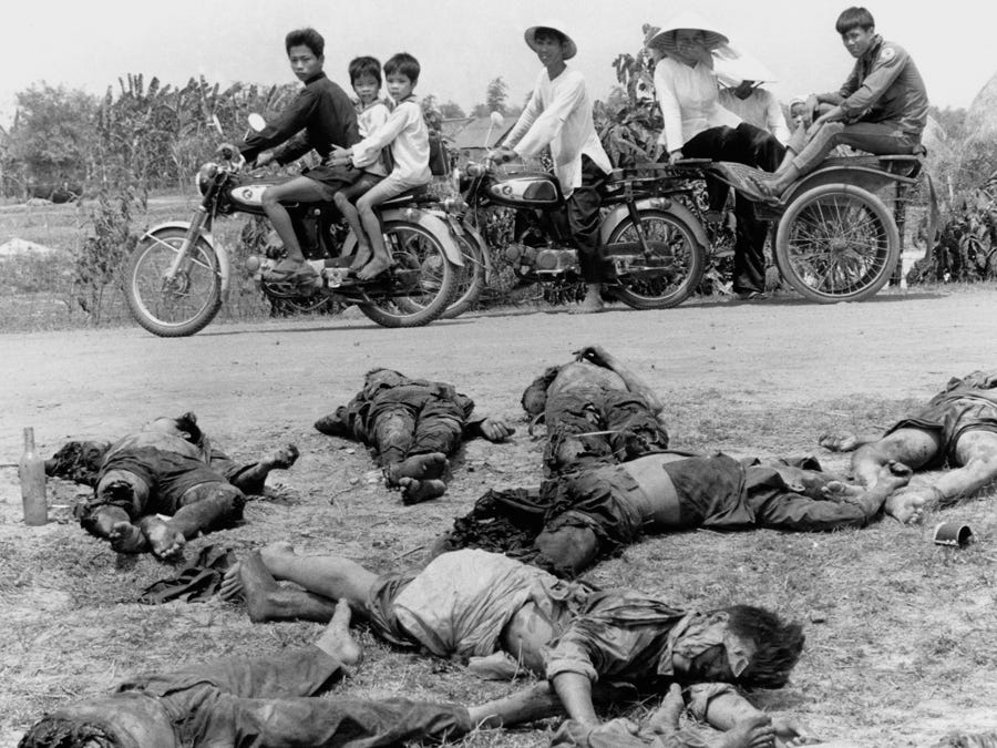 Children ride home from school past the bodies of 15 dead Viet Cong soldiers and their commander in the village of An Ninh in Vietnam's Hau Nghia province on May 8, 1972.
