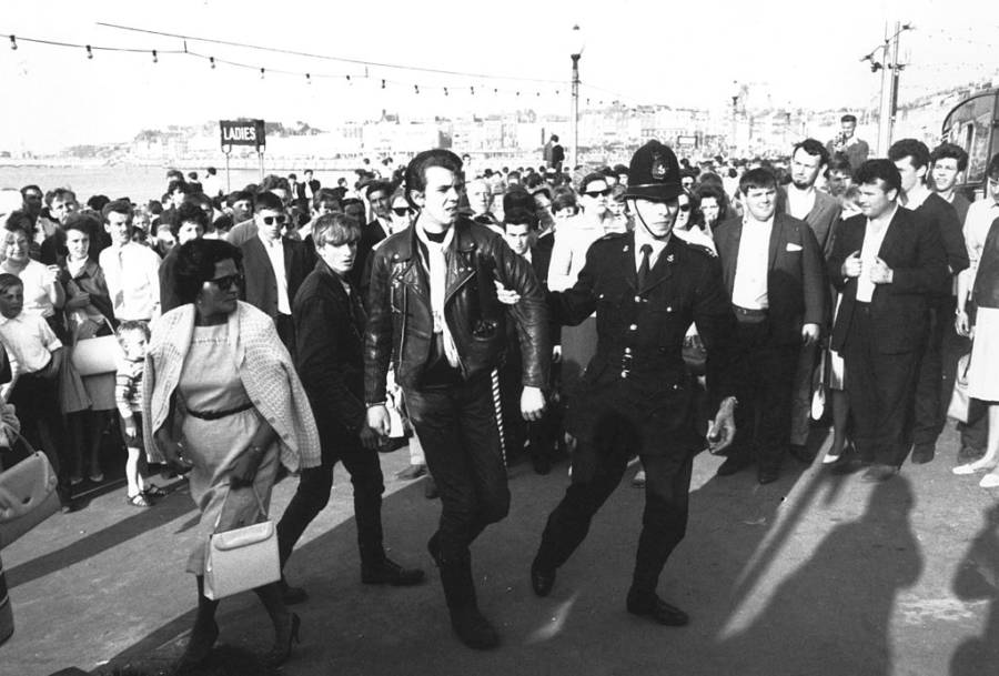 An officer leads a rocker away by his arm